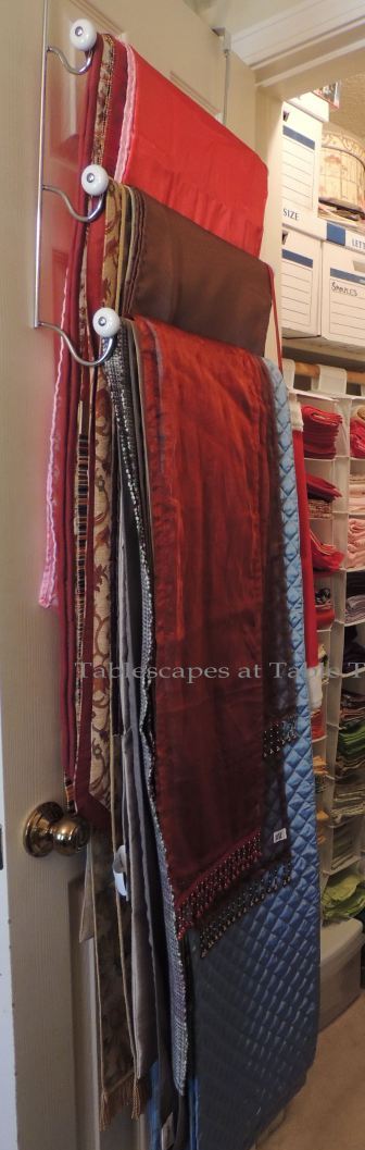 Hanging on a towel rack on the door are numerous table runner. The more casual runners are stored in the basement.