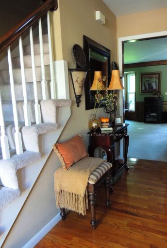 Foyer table with large basket of pine cones underneath, pheasant plates on sconce shelves